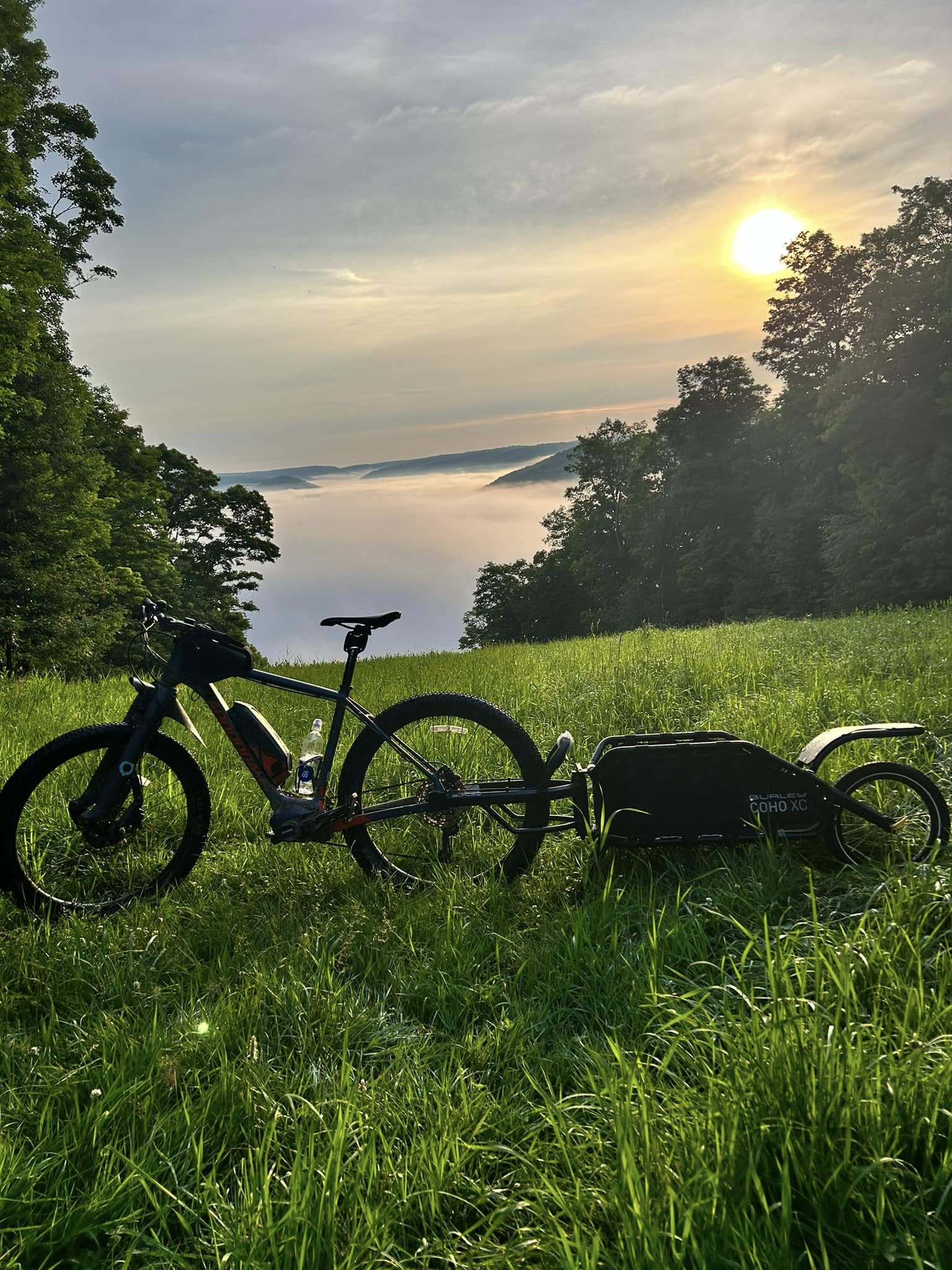 Mountain bike parked in a meadow above the clouds at sunrise near Ellicottville